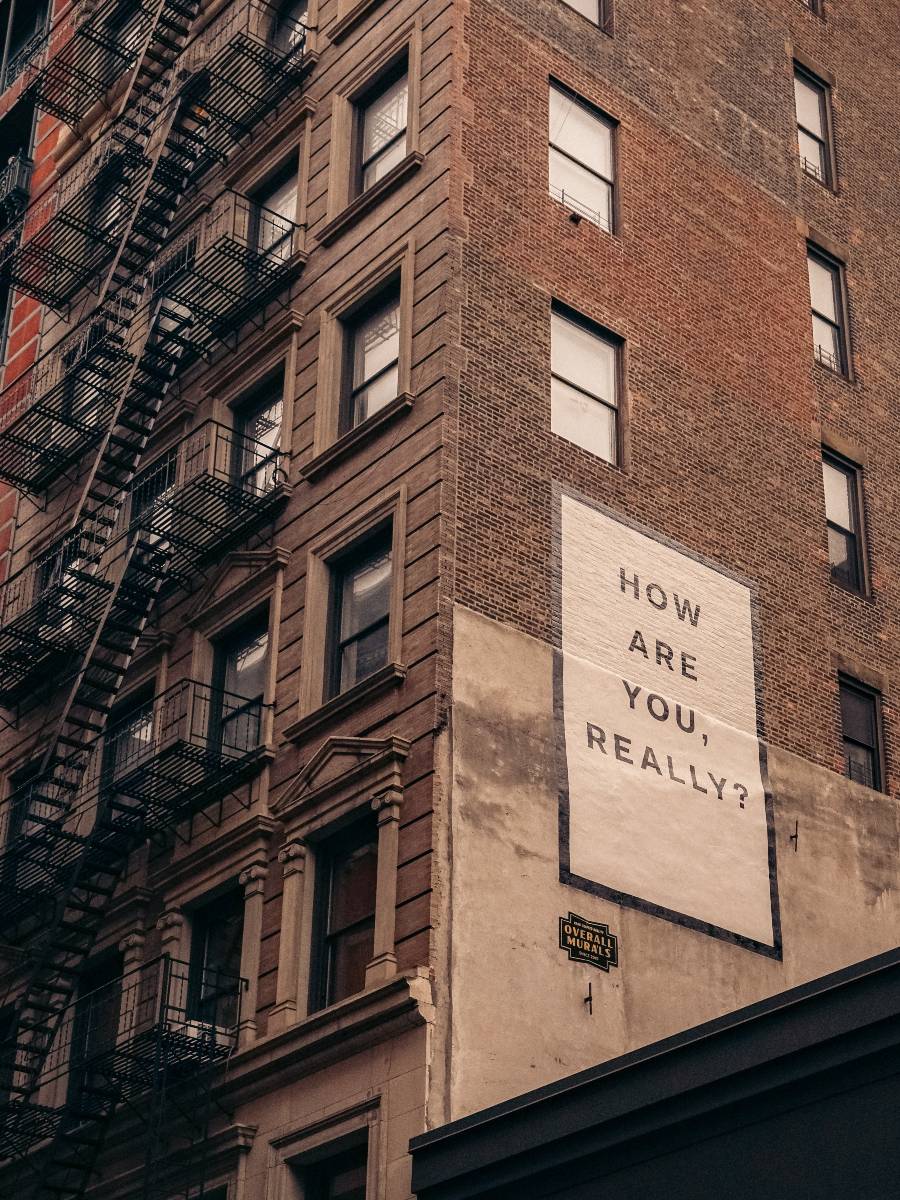 edificio ladrillo rojo con cartel how are you feeling como te sientes salud mental
