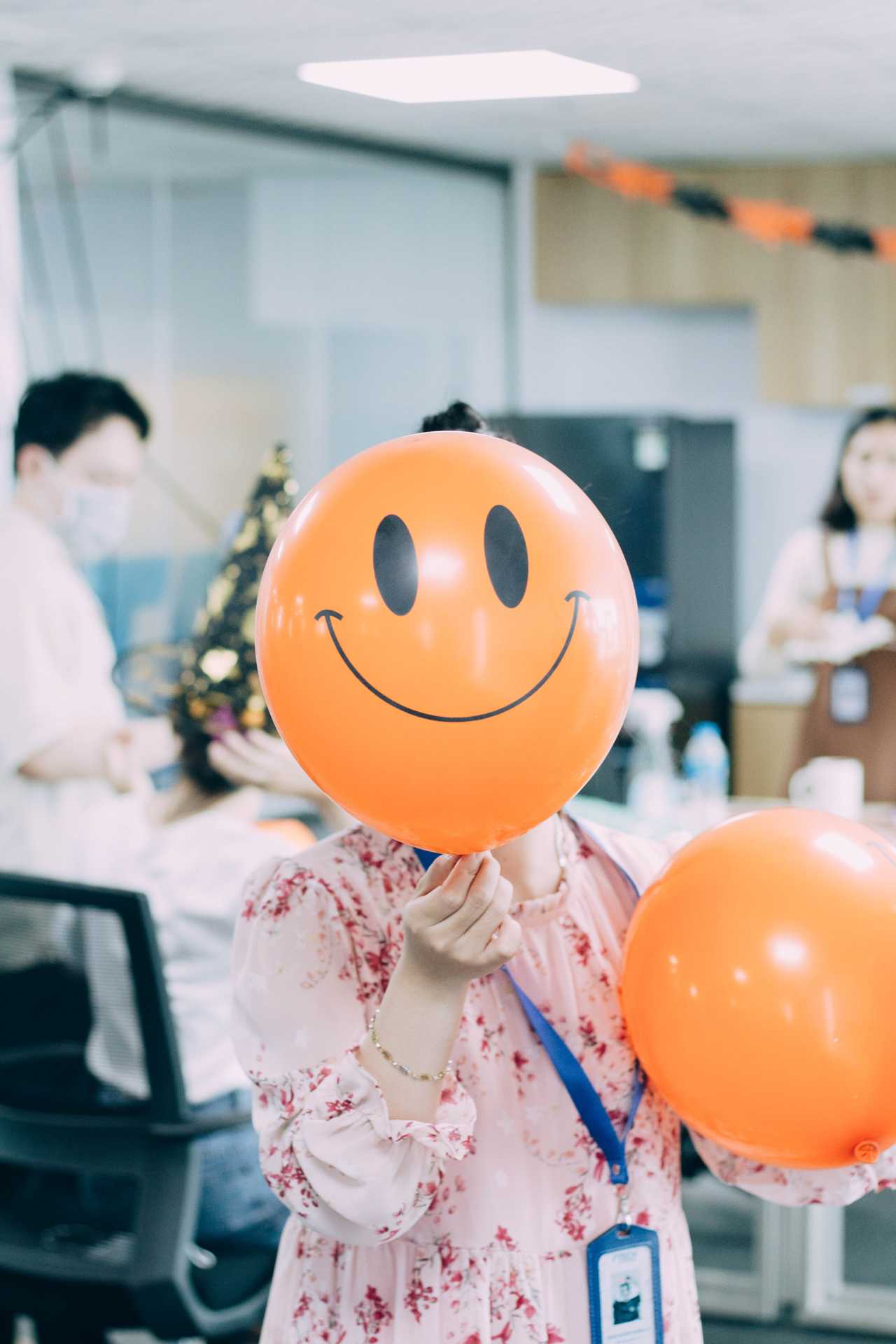 empleada oficina con globo naranja feliz sonrisa sindrome impostor cara mascara